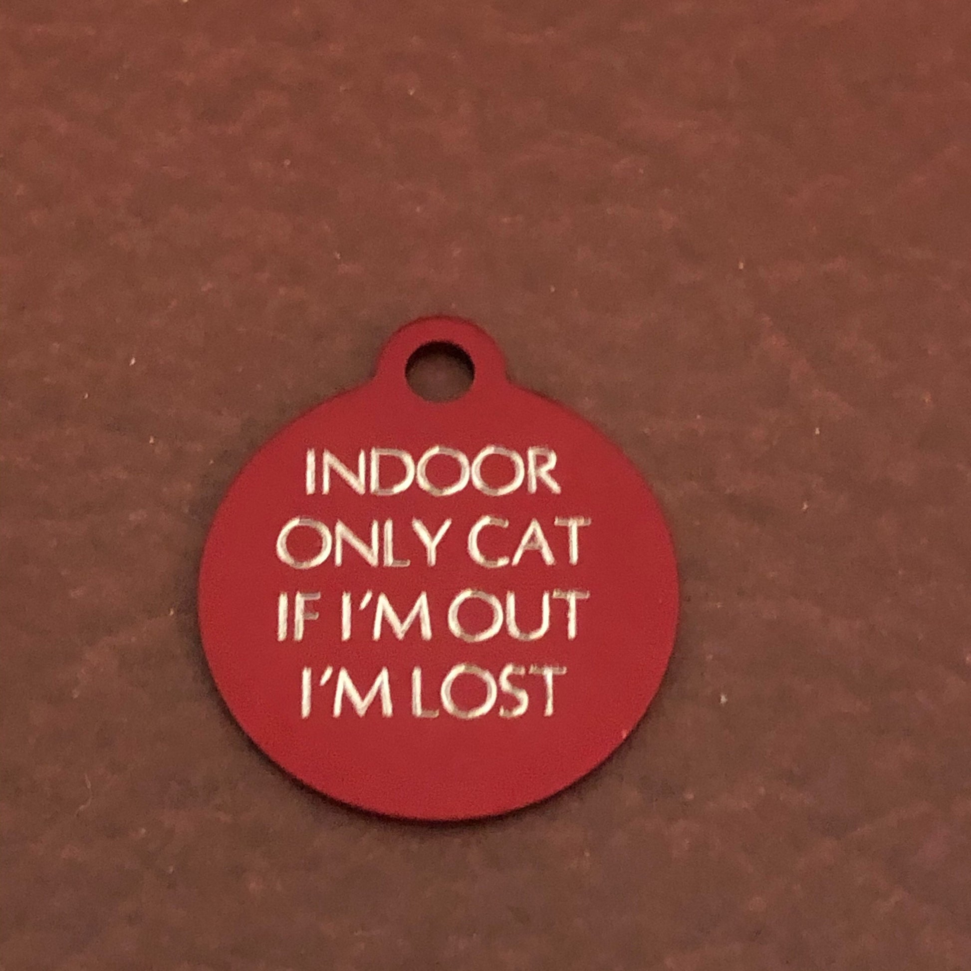 Small red circle tag that says: Indoor only cat If I&#39;m out I&#39;m lost. All engraved in capital letters.