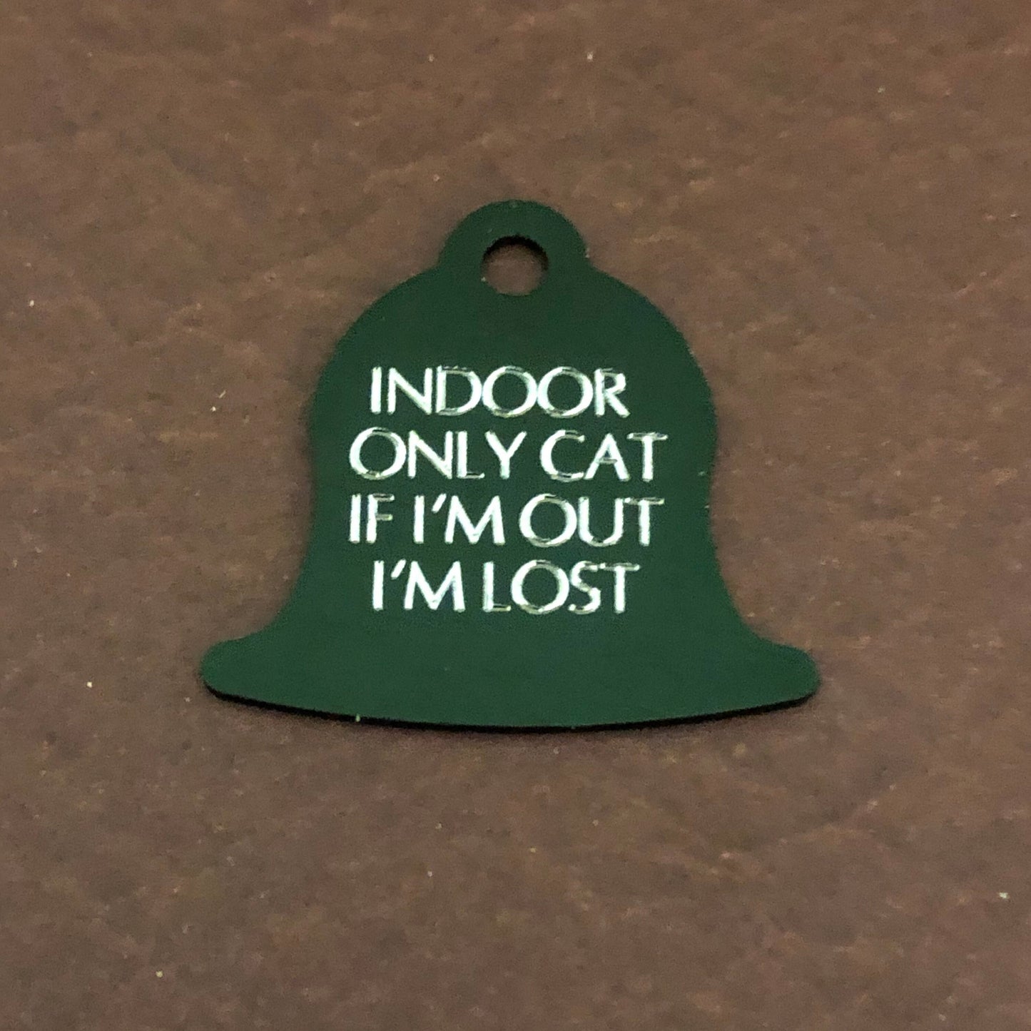 Small green bell tag that says: Indoor only cat If I&#39;m out I&#39;m lost. All engraved in capital letters.