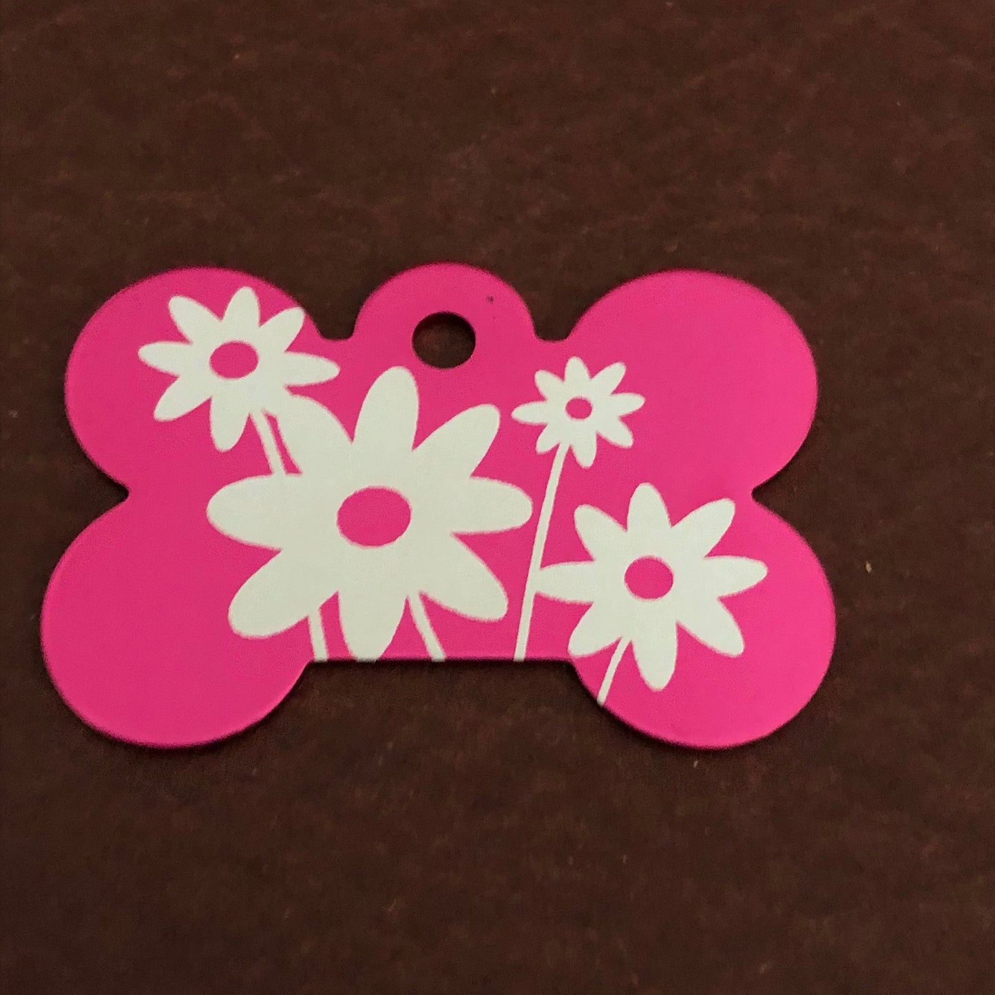 It is a large pink aluminum bone tag with a daisy floral design on it.
The Tag measures approximately 1 9/16&quot;W x 1 1/16&quot;H.