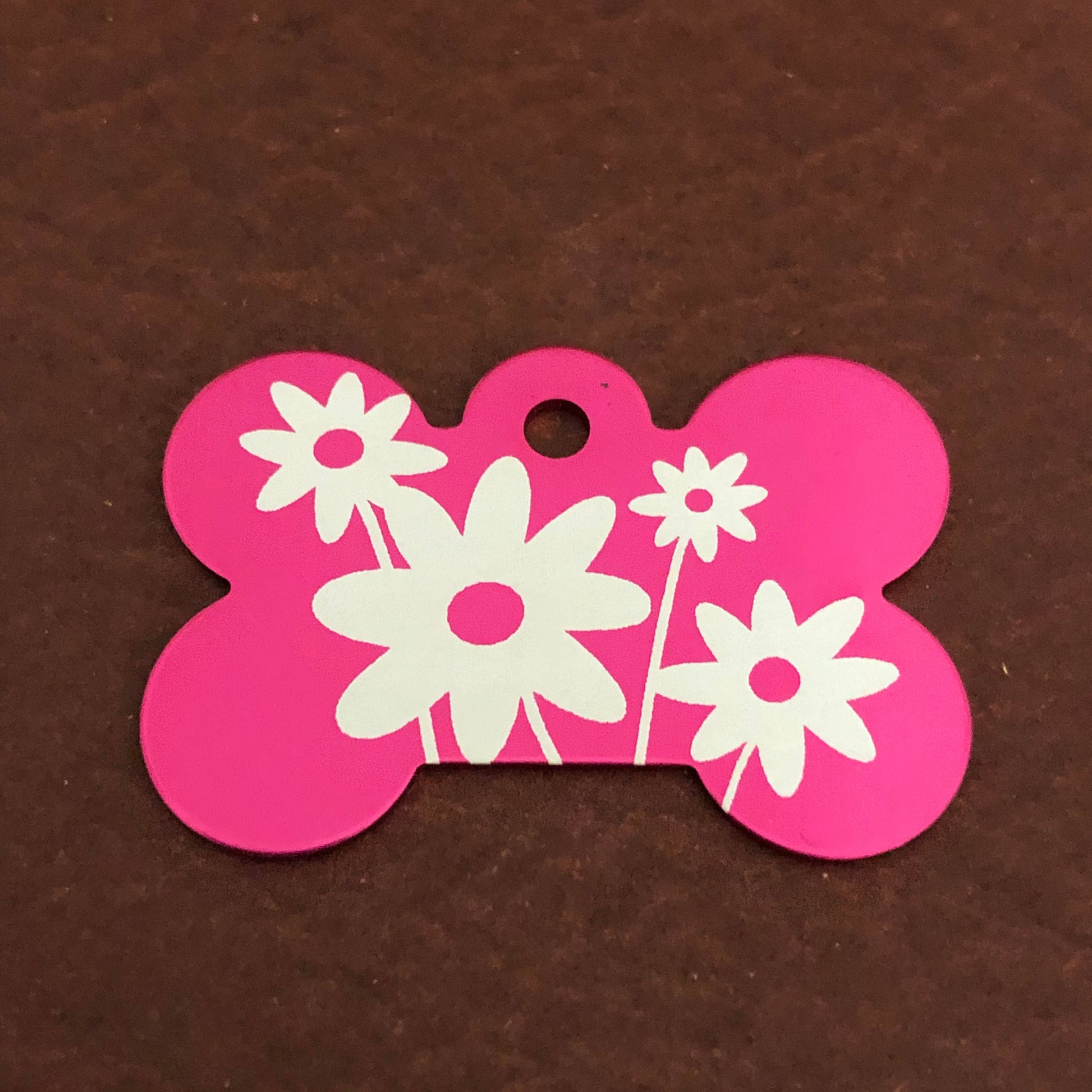 It is a large pink aluminum bone tag with a daisy floral design on it.
The Tag measures approximately 1 9/16&quot;W x 1 1/16&quot;H.