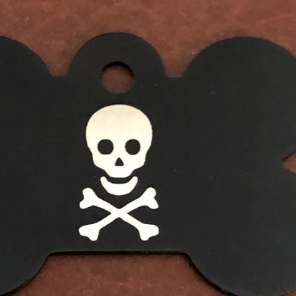 A close up of a  large black bone aluminum tag with a skull and bones on it.
The Tag measures approximately 1 9/16&quot;W x 1 1/16&quot;H.