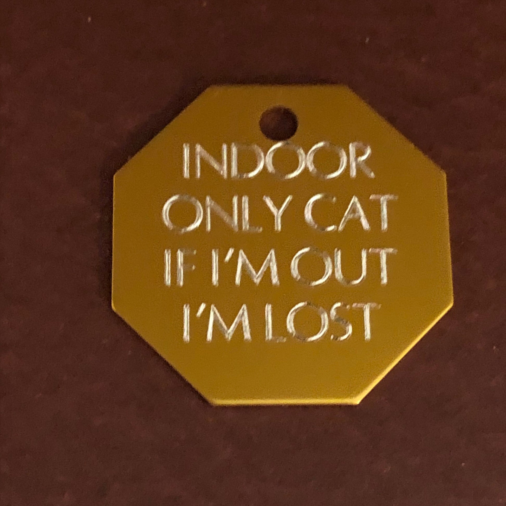 Large gold stop sign tag that says: Indoor only cat If I&#39;m out I&#39;m lost. All engraved in capital letters.